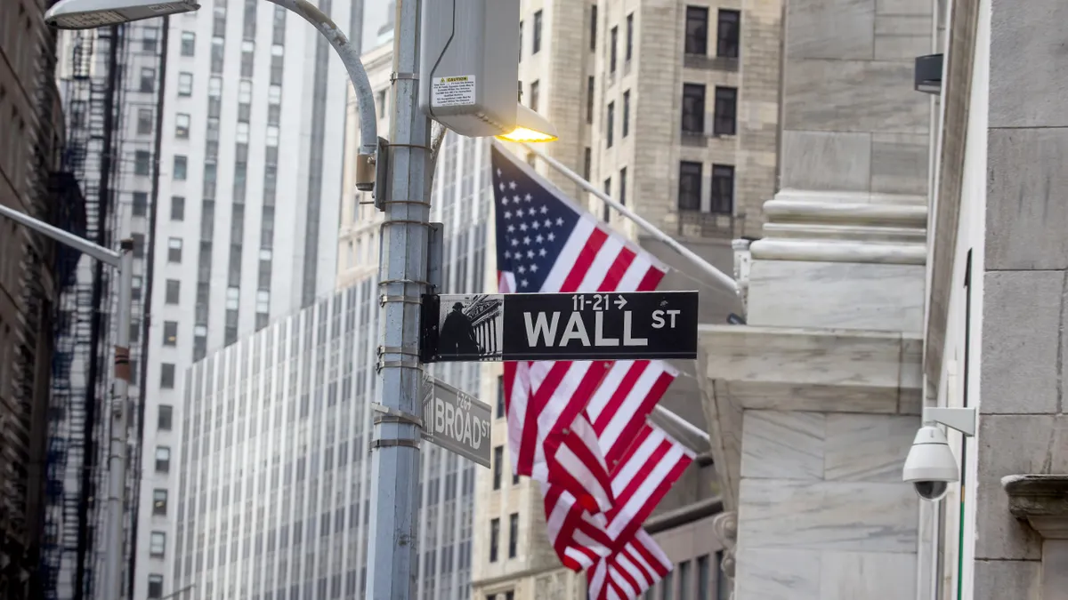 wall-street-nyc-american-flag Wall Street market plumbing shapes how investors hold assets. Analysts say centralized custody and settlement systems could matter more during crises.